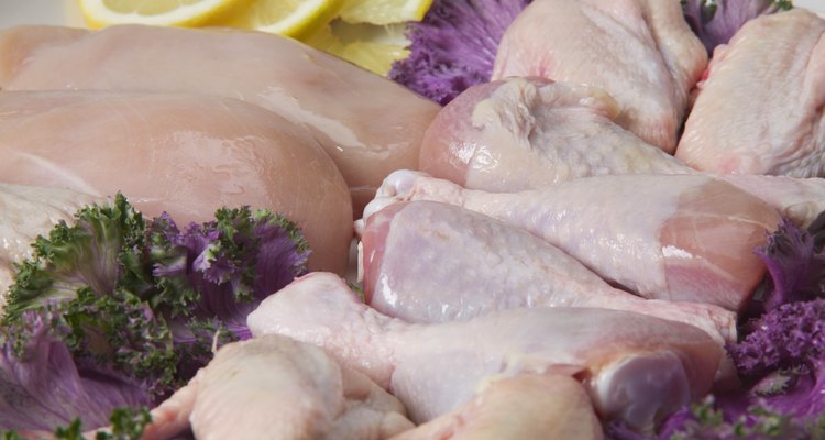 Tray of uncooked chicken breasts, thighs and legs with garnishes