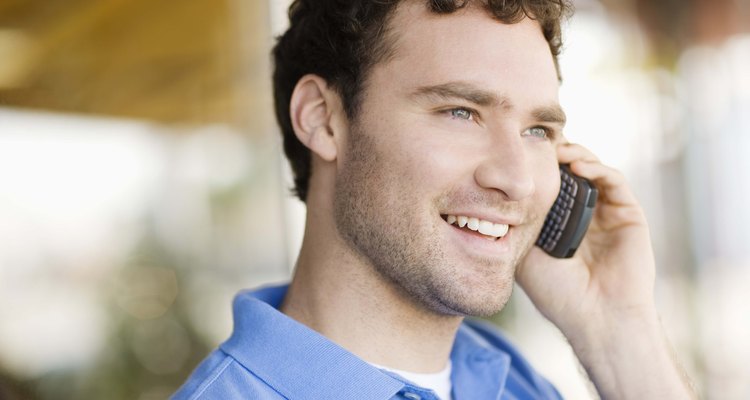 Un hombre sentando en un banco, hablando por su teléfono celular.