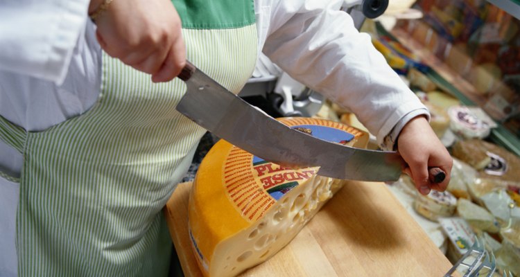 Woman Slicing Cheese in a Delicatessen