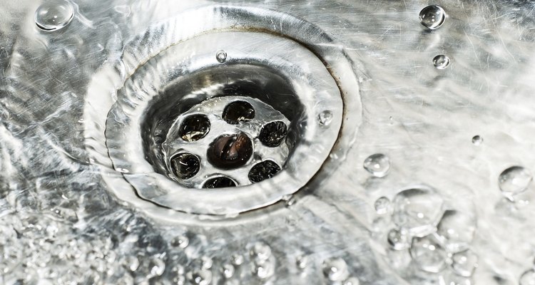 Stainless steel sink plug hole close up with water