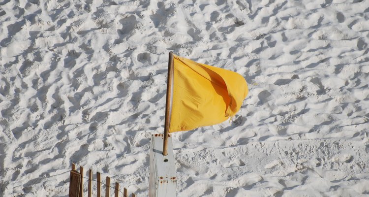 Una bandera de advertencia amarilla en la arena.
