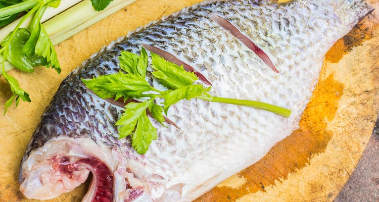 Fish and spices on a wooden cutting board.