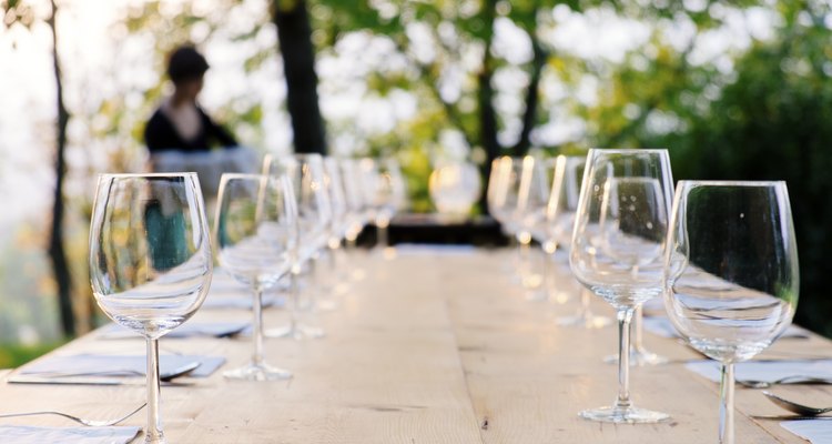 Copas vacías de agua y vino en una mesa al aire libre.