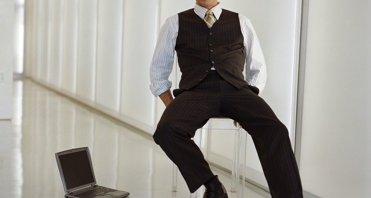 Businessman sitting on chair by laptop on floor, portrait