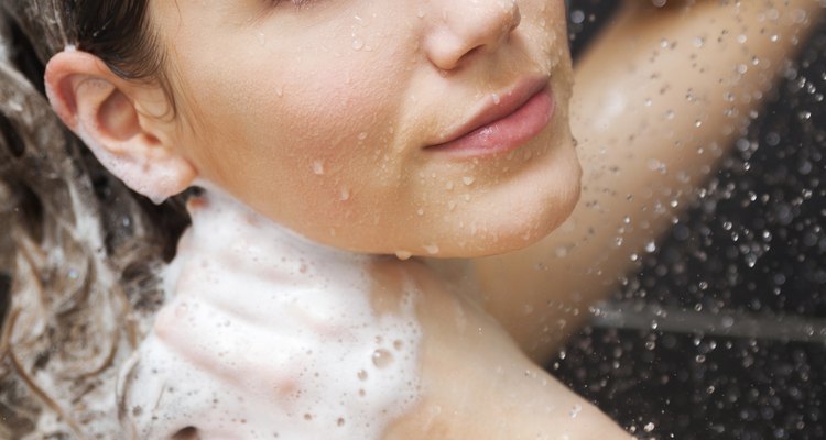 Una mujer sonriente, duchándose y lavando su cabello.
