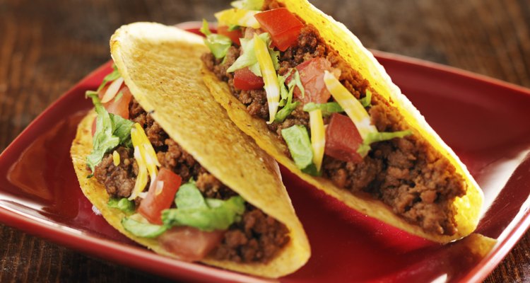 two beef hard shell tacos with cheese, lettuce and tomatoes