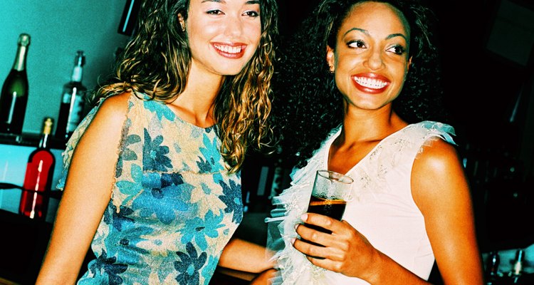 shot of two women standing at a bar counter with drinks