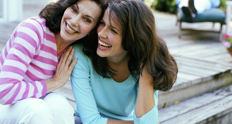 Mother and daughter sitting on garden deck, heads together, smiling