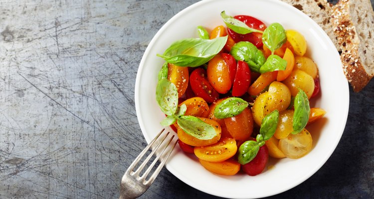 Fresh tomatoes with basil leaves in a bowl