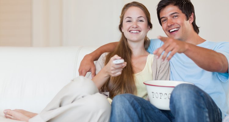 Happy young couple watching movie together on couch