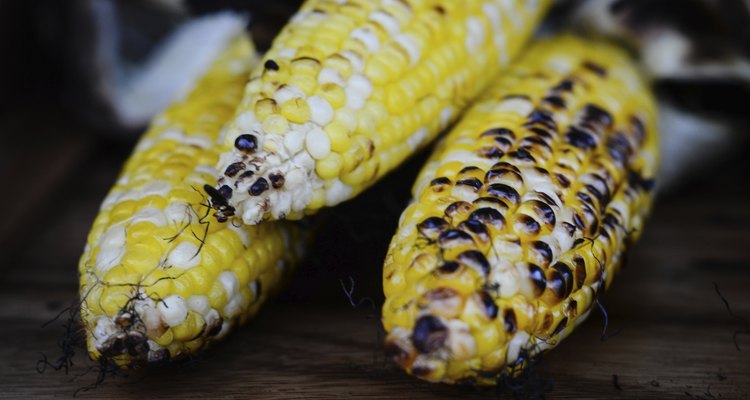 Roasted corn on the cob sitting on wood serving dish