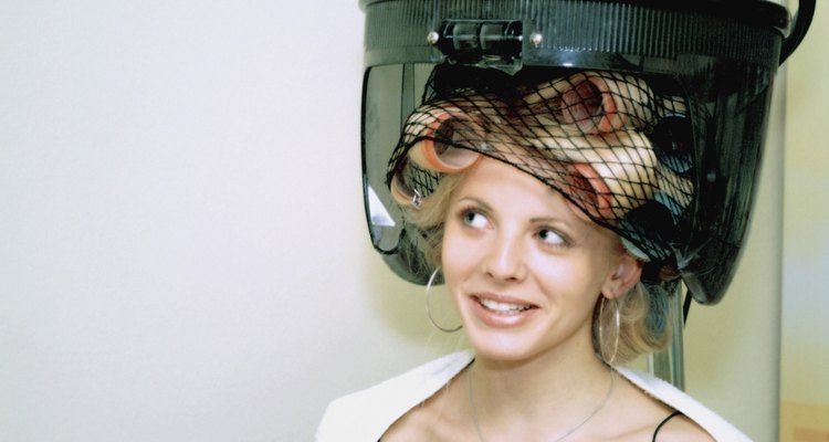 Close-up of a mid adult woman with rollers in her hair under a hair dryer