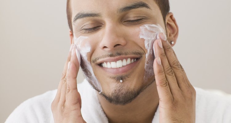 Young man spreading shaving cream on his cheeks