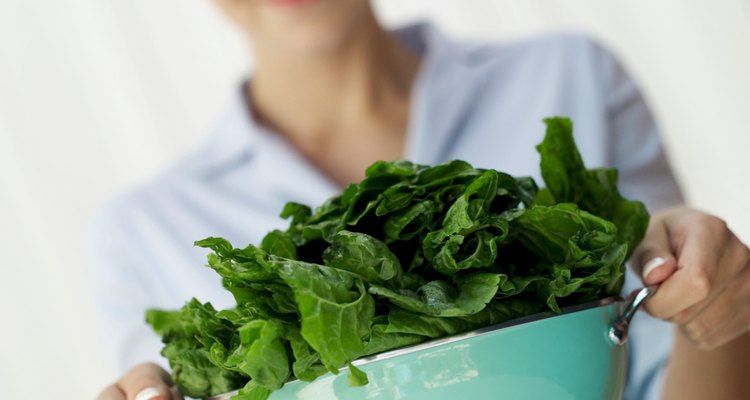 woman holding a colander of washed greens (selective focus)