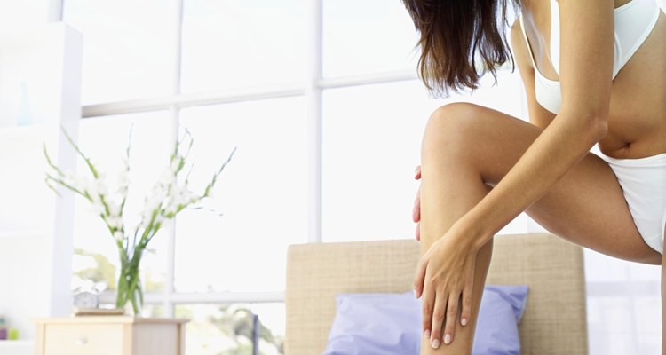 woman with leg up on the bed applying lotion