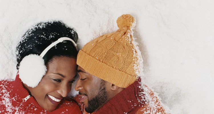 Couple Wearing Warm Clothing Lying in the Snow and Gazing at Each Other