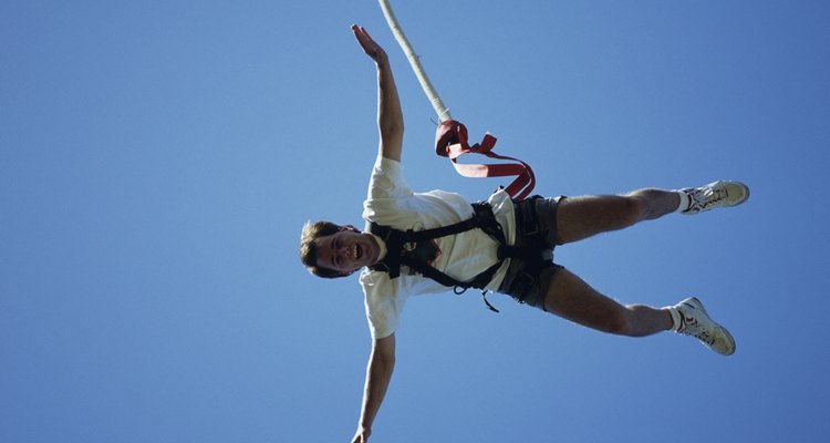 Man bungee jumping, seen against blue sky, view from below
