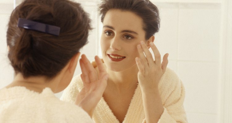 Woman applying cosmetics in mirror