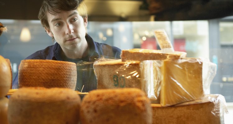 Young man looking at selection of cheeses, view through shop window