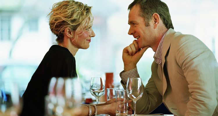 Couple sitting face-to-face at restaurant table, smiling