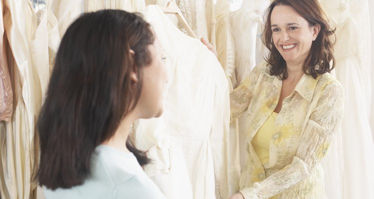 Two young women looking at wedding dresses in clothing store