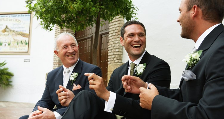 Groom with father and best man outdoors, smiling