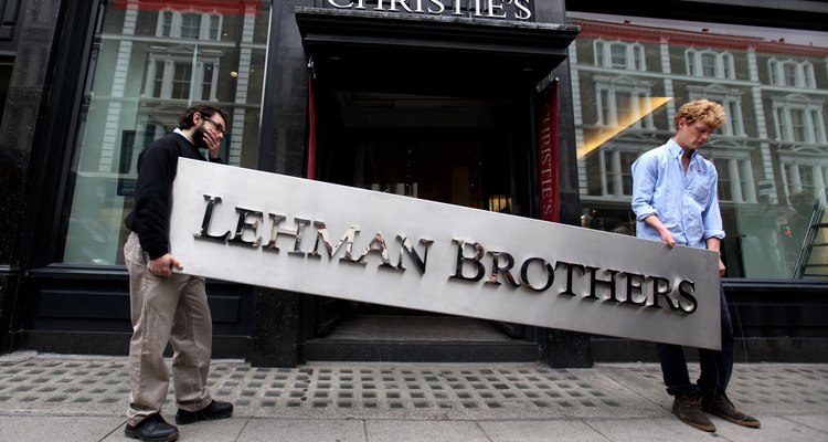 Dois funcionários da casa de leilões Christie's carregam para leilão a placa do banco Lehman Brothers, que faliu em 2008