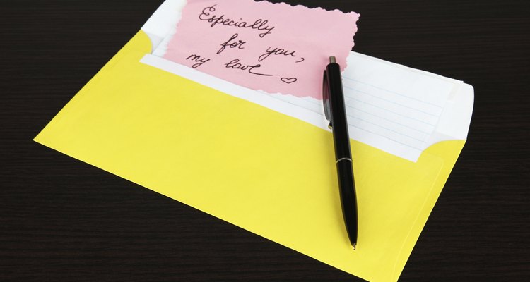 Note in envelope with pen on wooden background