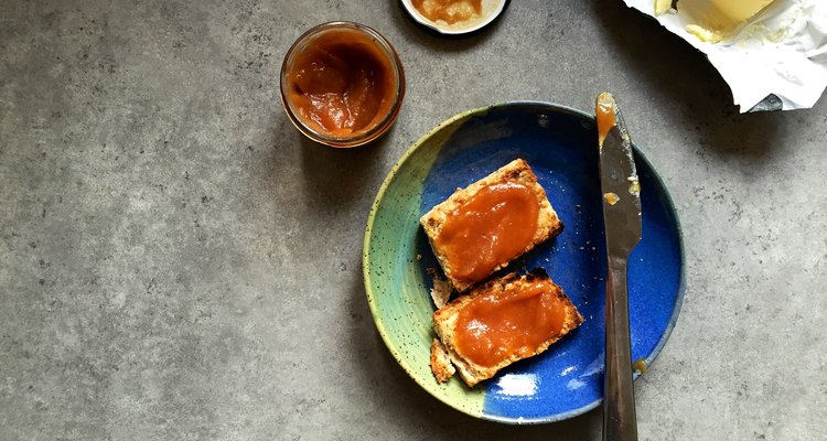 Toasted scone with apple butter on plate in home kitchen