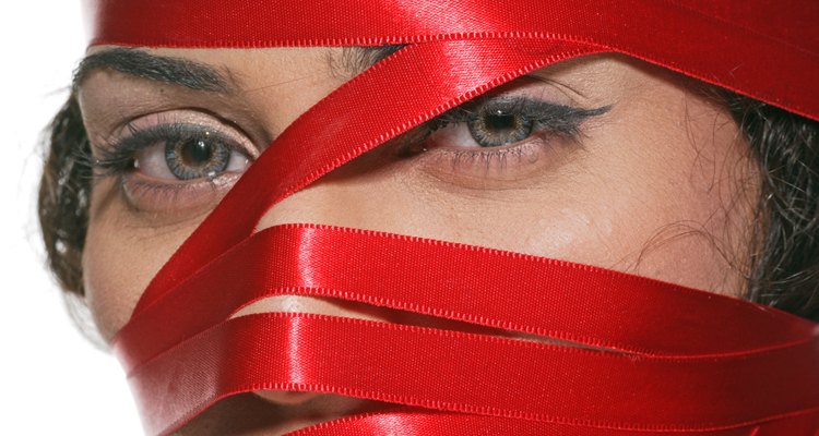 Young woman's face wrapped with a red ribbon