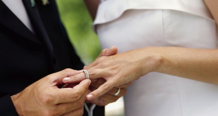 Novio colocando el anillo de bodas en el dedo de su novia.