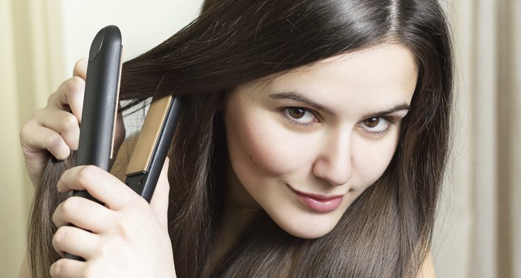 Beautiful young woman straightening hair