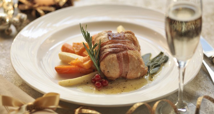 Turkey parcel wrapped in pancetta, stuffed with cranberry and orange and served with lemon and sage sauce with roasted winter vegetables, amid festive decorations