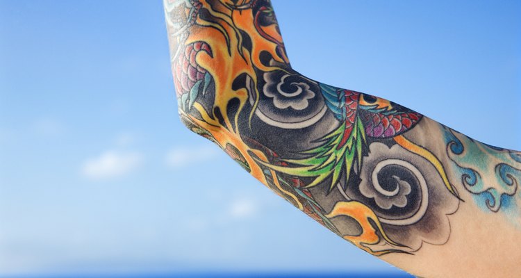 Close up of tattooed woman' || chr(39) || 's arm with Pacific Ocean in background in Maui, Hawaii, USA.