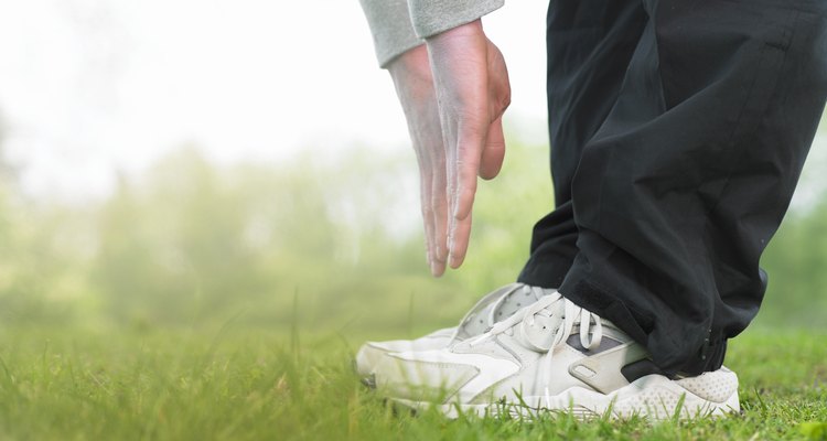 Young man doing exercises on grass, low section