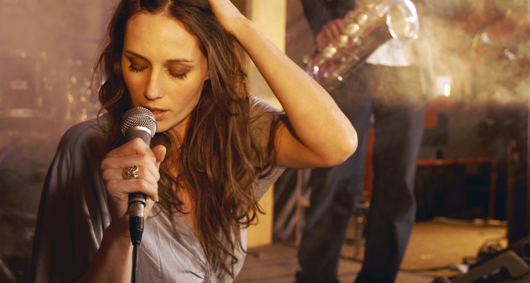 Female Singer Performing on Stage With a Man in the Background Playing a Saxophone