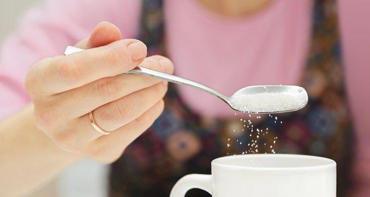 woman holds a spoon and strews sugar to mug