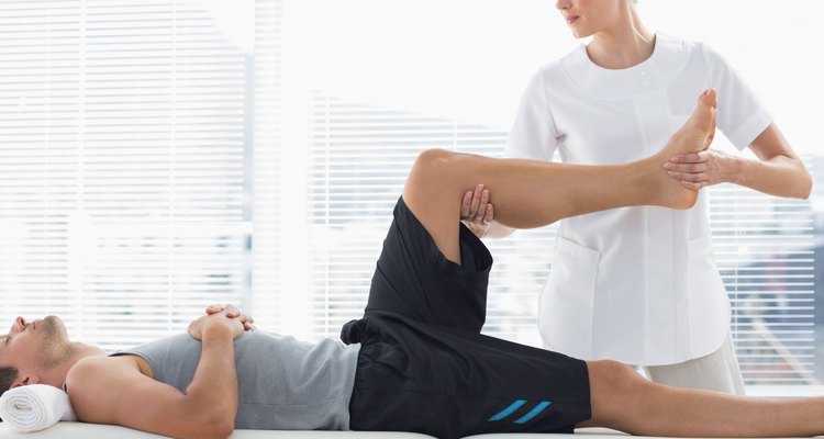 Physiotherapist massaging leg of man
