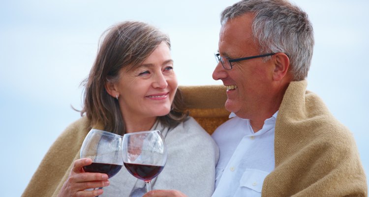 Close-up of romantic senior couple holding wineglasses on the beach