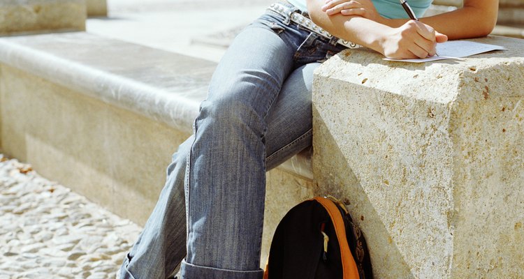 Young woman sitting in sunshine on step writing letter