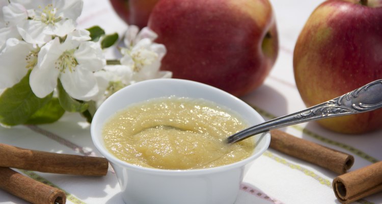 White bowl with applesauce, apples, cinnamon sticks