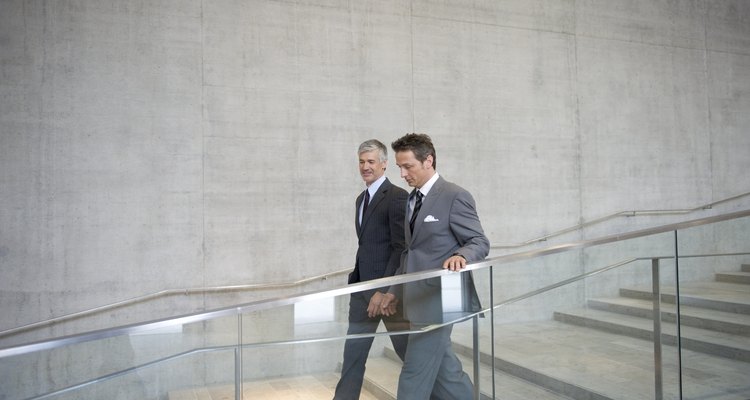 Businessmen in discussion as they walk down staircase