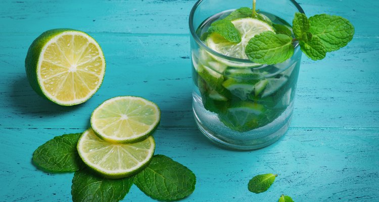 A glass of mojito cocktail with lime and mint on green wooden background, empty clean place for your text