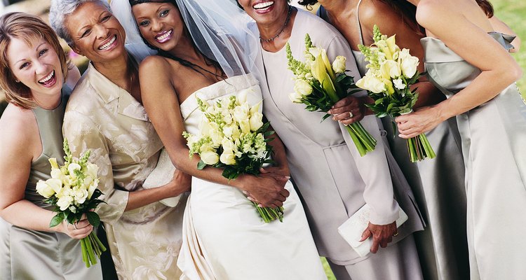 Bride, Bridesmaids and Mothers Stand Side-by-Side in the Grounds of a Wedding Reception