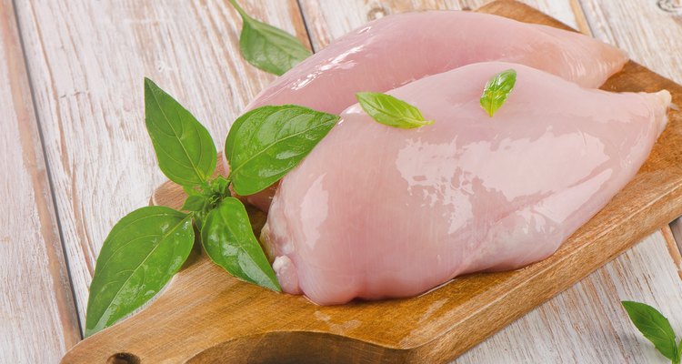 Raw chicken breast fillets on a cutting board.