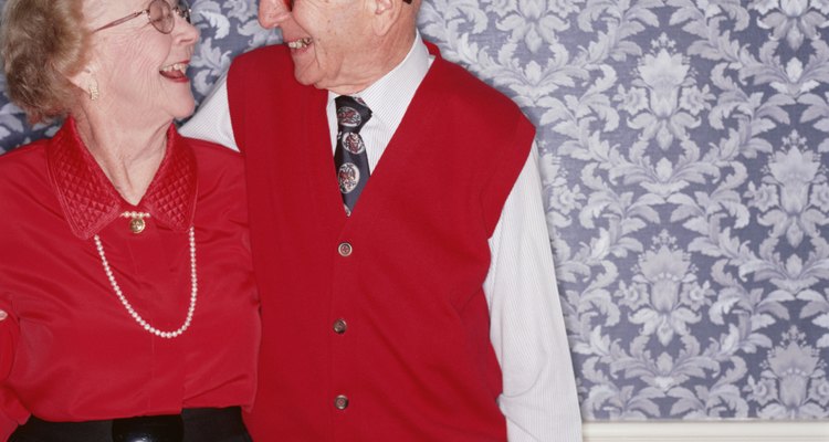 Senior couple standing together laughing, indoors, portrait