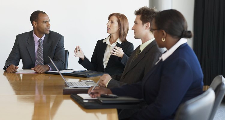 Business people at conference table, woman making hand gestures
