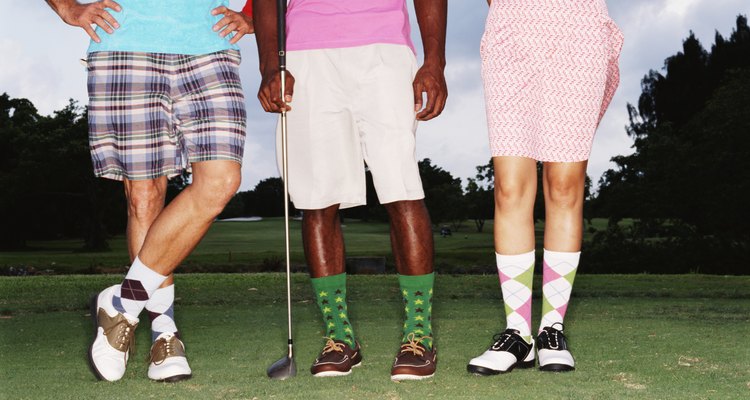 Three golfers standing in row on golf course, low section