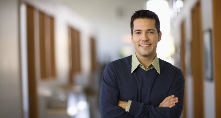 Businessman standing in hallway of office, arms crossed