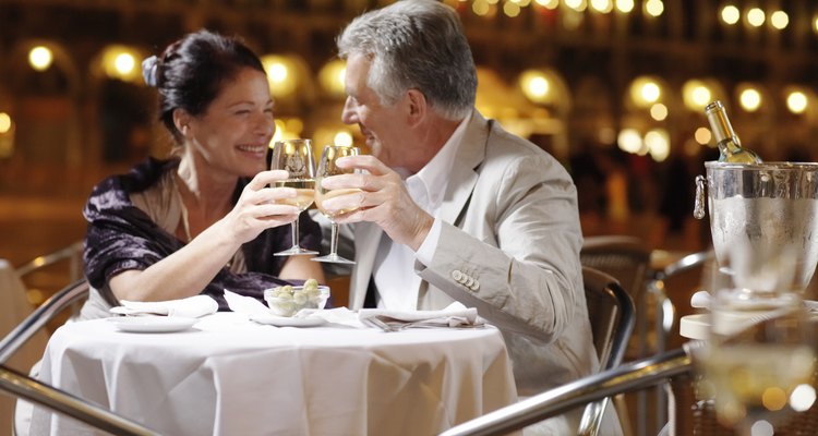 Couple at restaurant in square, toasting drinks, smiling, night